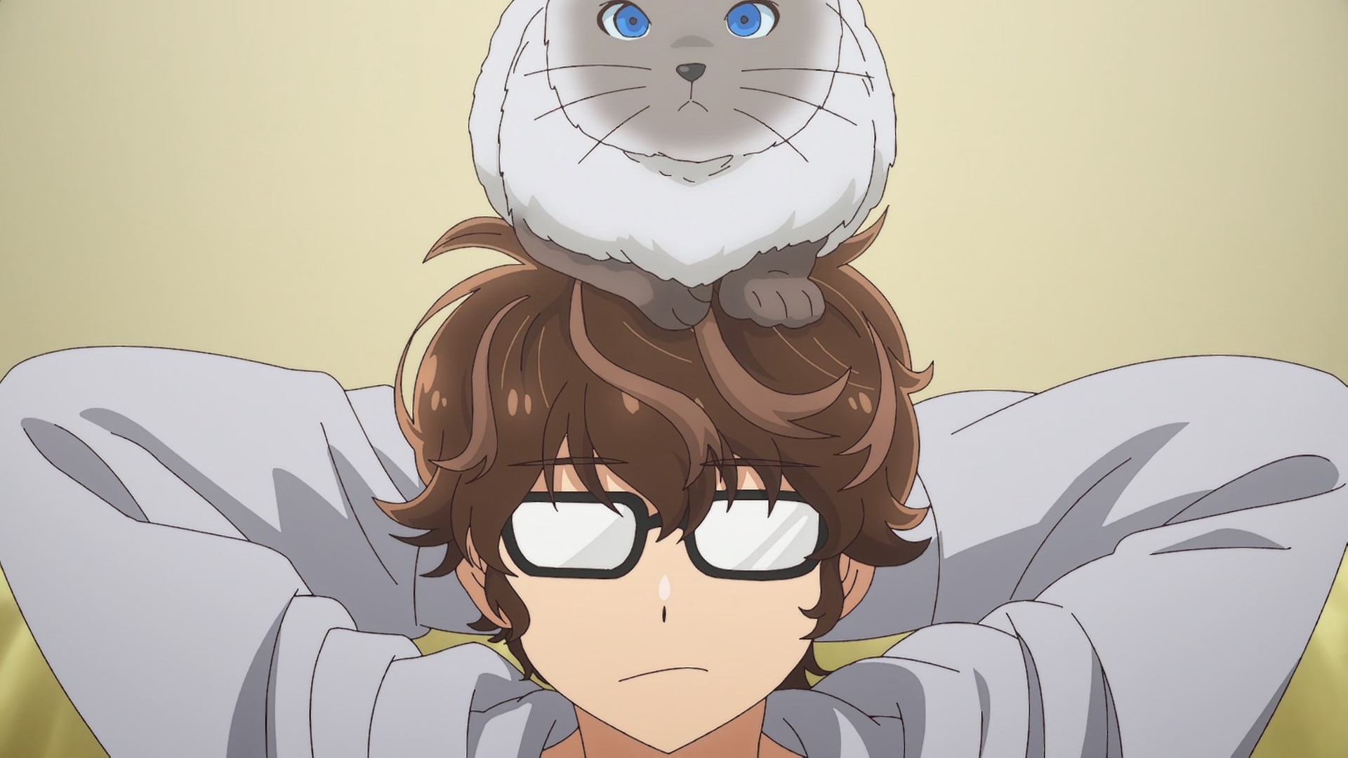 A blue eyed siamese looking cat sits on top a glasses wearing, shaggy haired dude in lounge wear